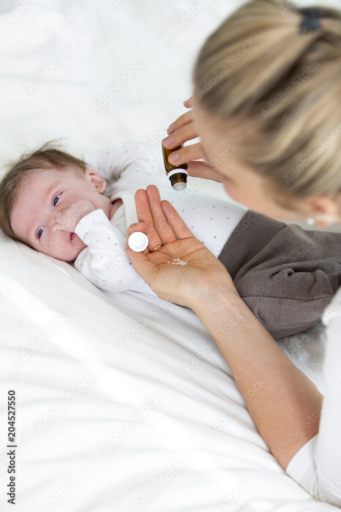beautiful young mother is giving her cute baby daughter homeopathic globules - obrazy, fototapety, plakaty 
