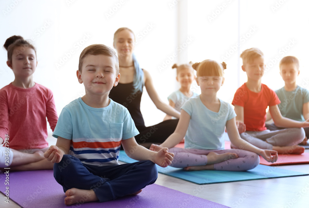 Little children and their teacher practicing yoga in gym - obrazy, fototapety, plakaty 
