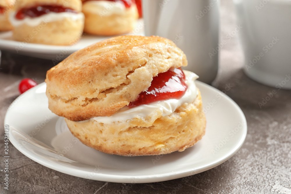 Tasty scone with clotted cream and jam on plate, closeup Tasty scone with clotted cream and jam on plate, closeup
