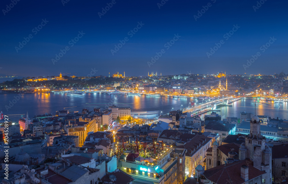 Long exposure panoramic cityscape of Istanbul at a warm calm evening from Galata to Golden Horn gulf. Wonderful romantic old town at Sea of Marmara. Bright light of street lighting. Istanbul. Turkey.