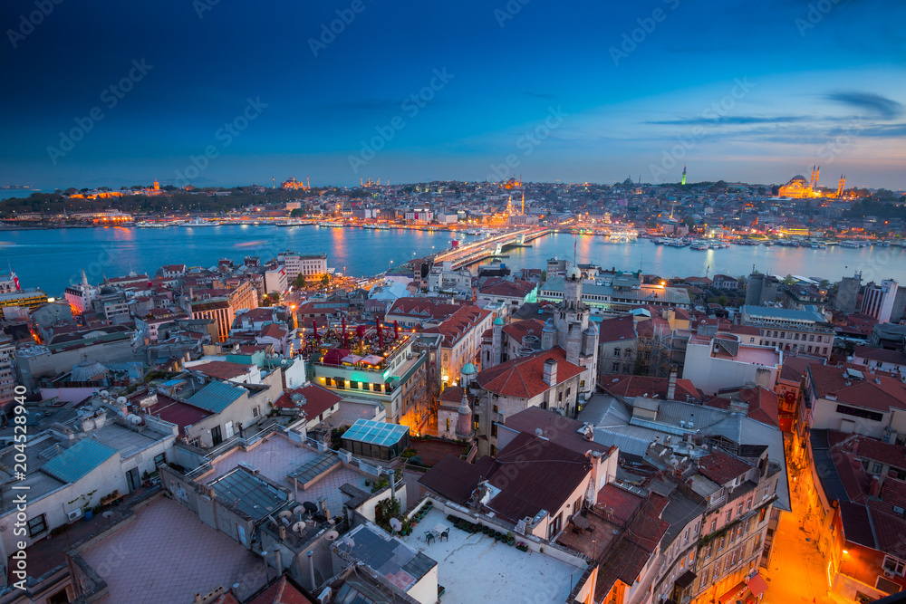 Naklejka premium Long exposure panoramic cityscape of Istanbul at a warm calm evening from Galata to Golden Horn gulf. Wonderful romantic old town at Sea of Marmara. Bright light of street lighting. Istanbul. Turkey.