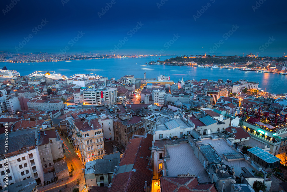 Naklejka premium Long exposure panoramic cityscape of Istanbul at a warm calm evening from Galata to Golden Horn gulf. Wonderful romantic old town at Sea of Marmara. Bright light of street lighting. Istanbul. Turkey.