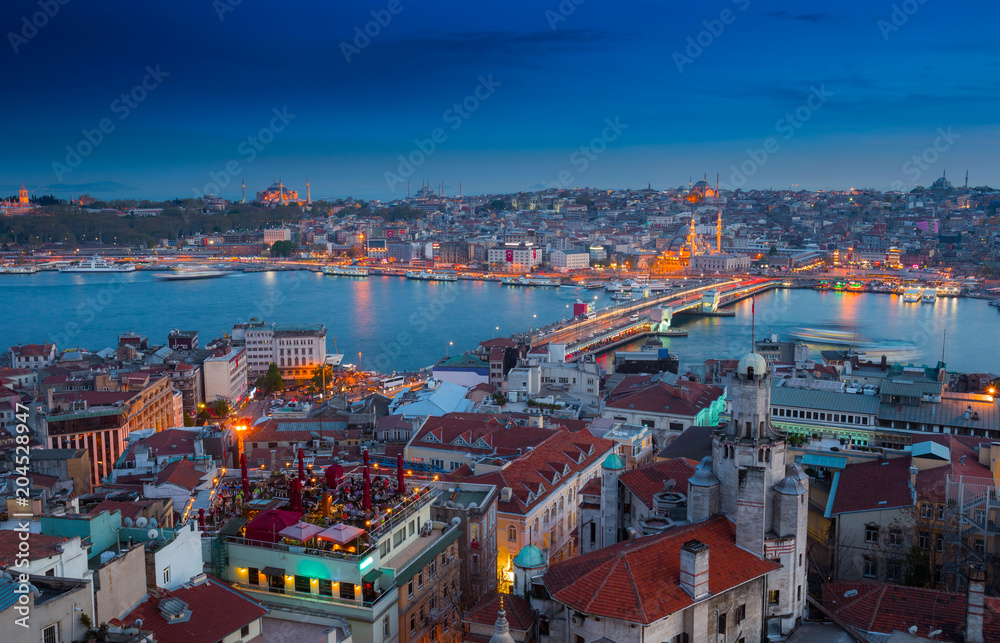 Obraz premium Long exposure panoramic cityscape of Istanbul at a warm calm evening from Galata to Golden Horn gulf. Wonderful romantic old town at Sea of Marmara. Bright light of street lighting. Istanbul. Turkey.