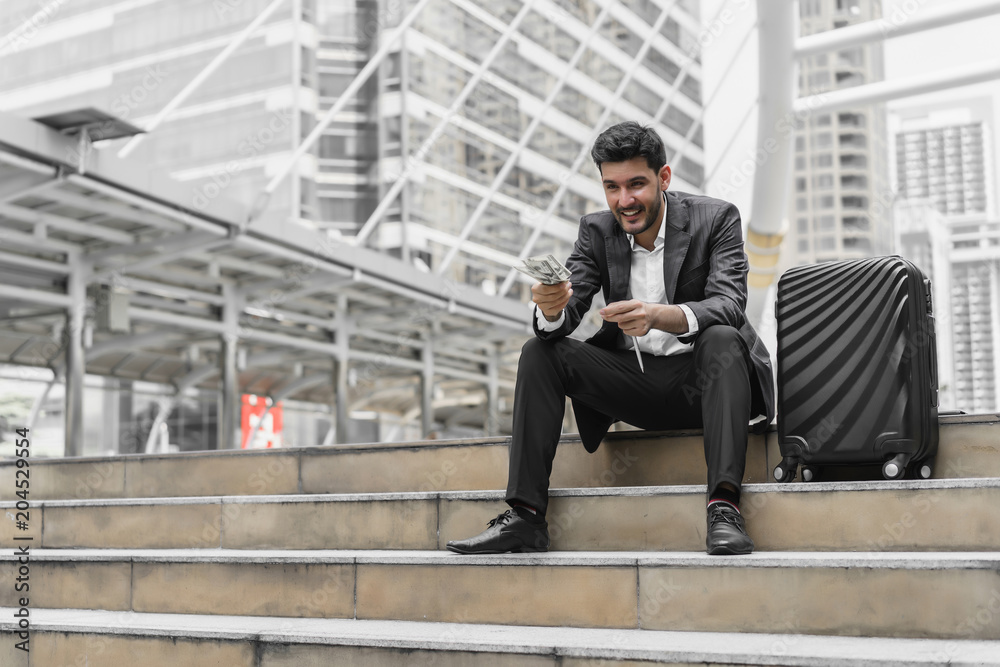 Businessman show money and sitting on stairs at outdoors with luggage. Concept of business finance investment, benefit, cost, deposit, guarantee, borrow and debt credit. Businessman show money and sitting on stairs at outdoors with luggage. Concept of business finance investment, benefit, cost, deposit, guarantee, borrow and debt credit.