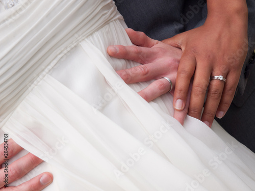 Bride and Groom Hands and rings on wedding dress close up
