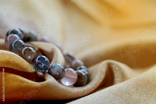 luxurious variegated mineral Rutile Quartz or  Venus hair stone bracelet on golden fabric background. Amulet accessories for good good lucky fortune and happy life 
