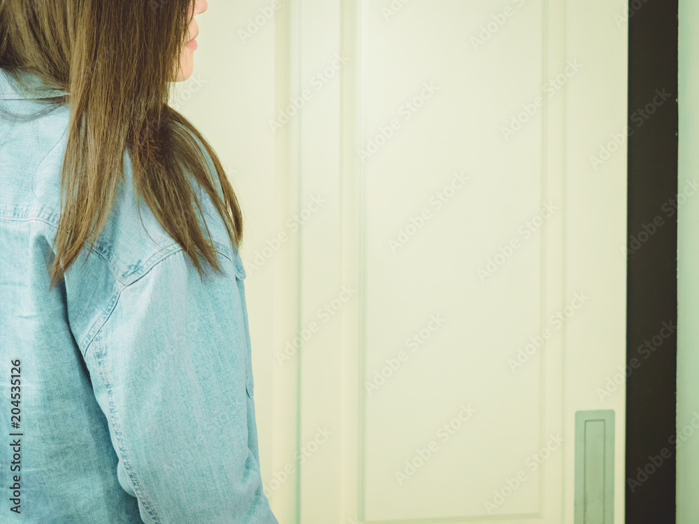 backside of asian hipster girl (25s to 35s) with blue jacket jean are waiting in front of the white door backside of asian hipster girl (25s to 35s) with blue jacket jean are waiting in front of the white door