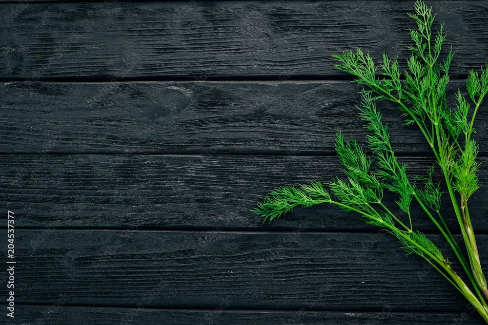 Fresh green dill. On a black wooden background. Healthy food. Top view. Copy space. Fresh green dill. On a black wooden background. Healthy food. Top view. Copy space.