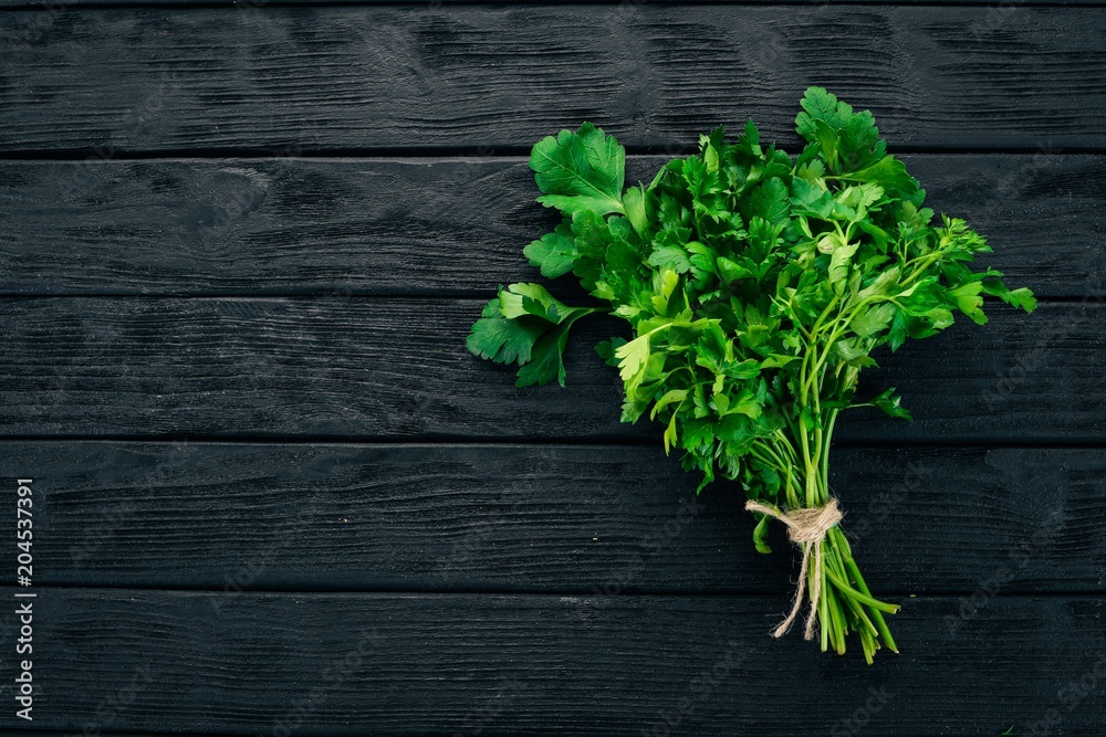 Fresh parsley. On a black wooden background. Healthy food. Top view. Copy space. Fresh parsley. On a black wooden background. Healthy food. Top view. Copy space.