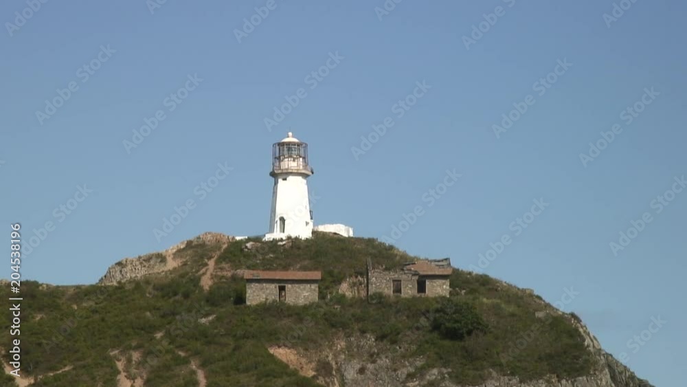 Lighthouse seamark on green stony rocks coastline beach in Japan Sea. Calmness and silence. Rest and tourism in beautiful place. Unique landscape and background. Lighthouse seamark on green stony rocks coastline beach in Japan Sea. Calmness and silence. Rest and tourism in beautiful place. Unique landscape and background.