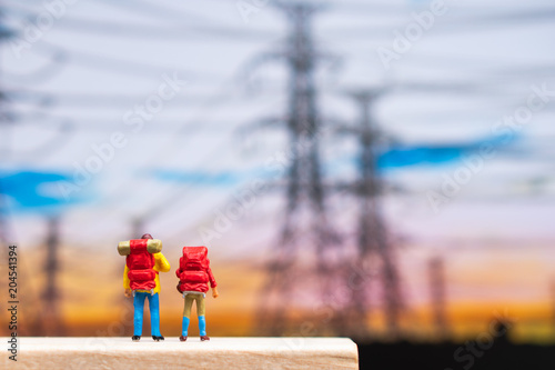 Miniature people, couple backpacker standing in front of electric pole using as travel and exploring concept