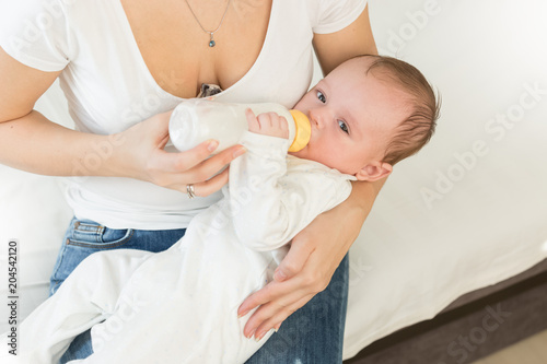 Toned photo of young woman giving bottle of milk to her baby boy