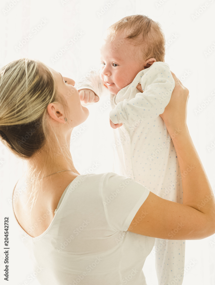 Portrait of happy young mother holding and looking at her 3 months old baby Portrait of happy young mother holding and looking at her 3 months old baby