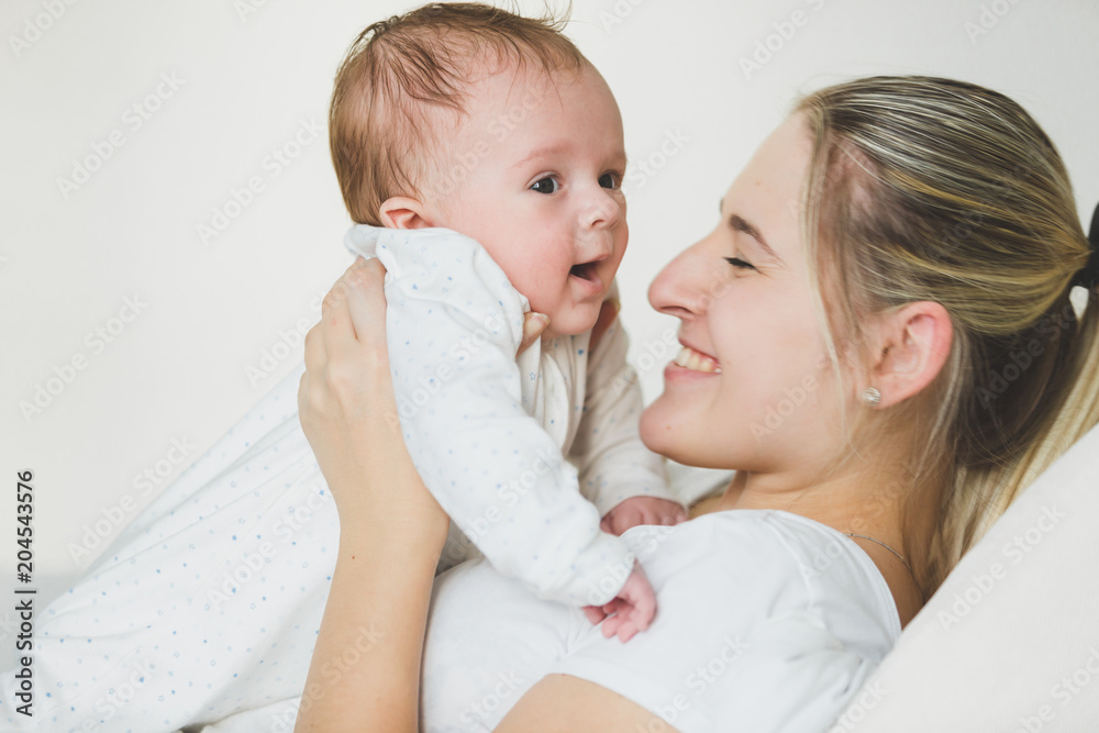 Toned portrait of lying young woman holding her 3 months old baby Toned portrait of lying young woman holding her 3 months old baby