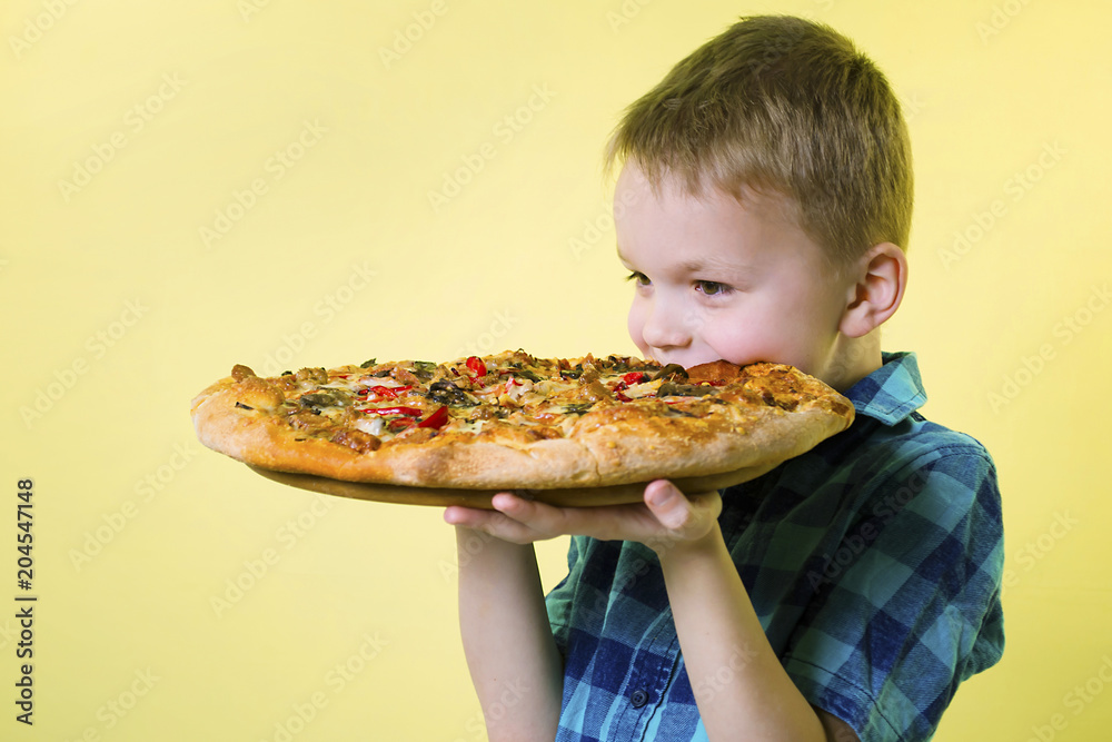 funny boy eating a big pizza on a bright yellow background funny boy eating a big pizza on a bright yellow background