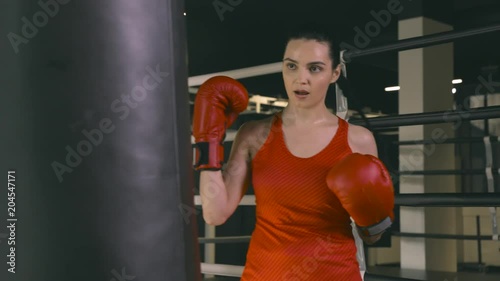 Young woman in boxing gloves hitting a boxing bag. Slow motion photo