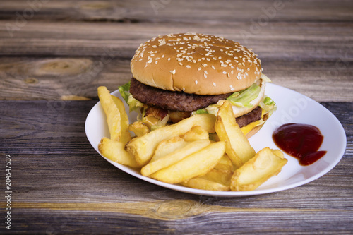 fast food hamburger with french fries on an old wooden background