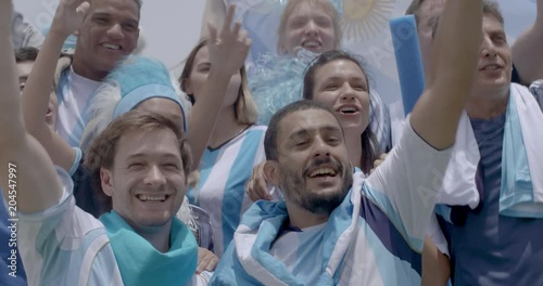 Group of Argentinian football fans cheering at football match