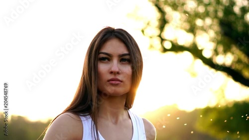 Young beautiful woman listening music at park while running. Portrait of smiling sporty girl with earphone looking at camera at park in autumn. Woman athlete looking at camera during winter sunset. photo