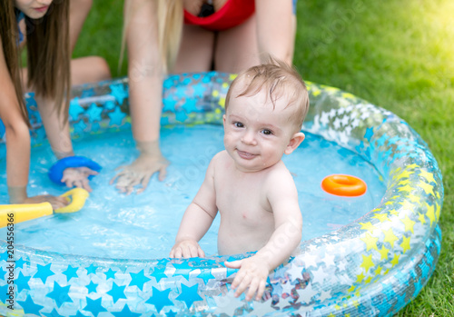 Portrait of happy smiling toddler boy having fun in inflatable swimming pool with family © Кирилл Рыжов