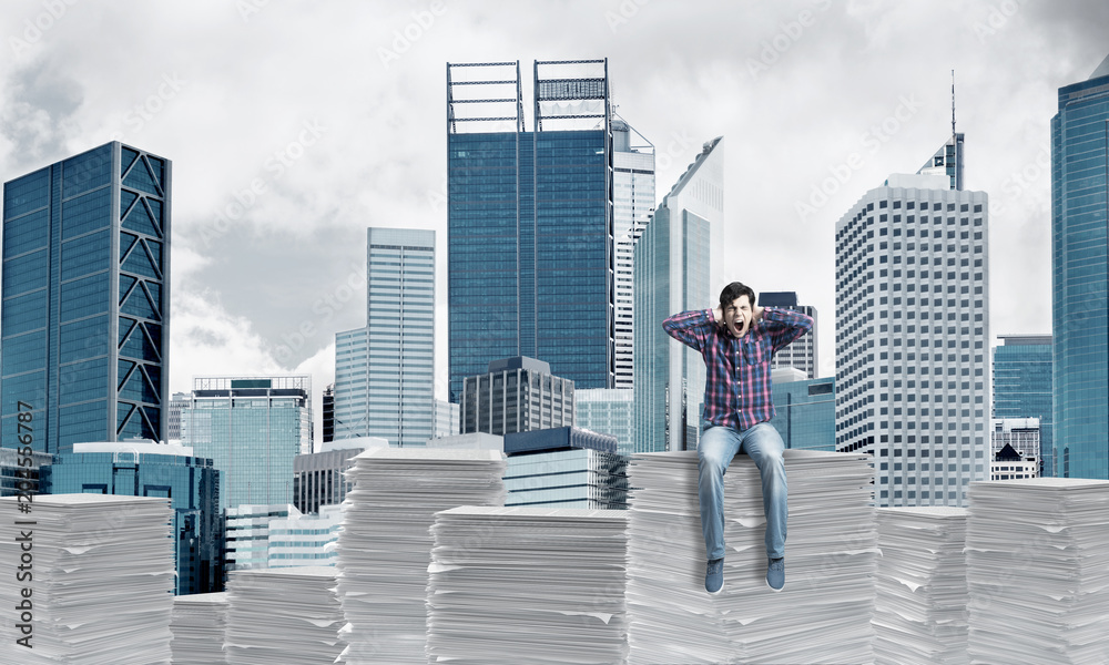 Attractive man sitting on pile of paper documents. Attractive man sitting on pile of paper documents.