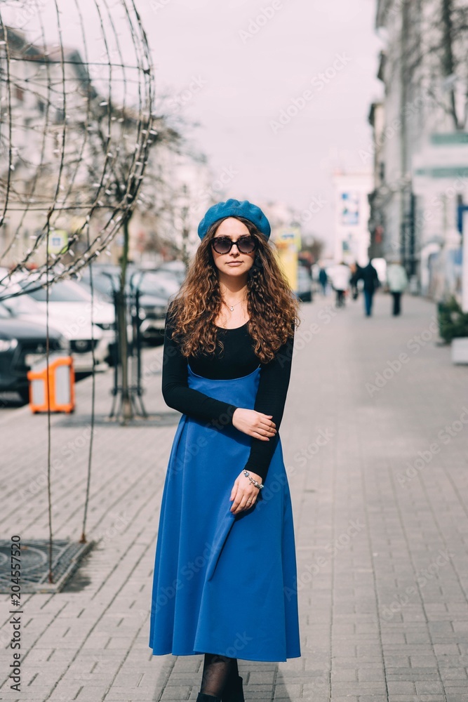 long-haired young woman in a blue beret and sunglasses walking around the city. long-haired young woman in a blue beret and sunglasses walking around the city.