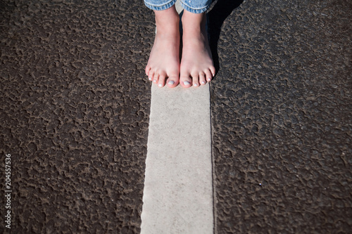 bare feet of women in jeans stand on the road markings