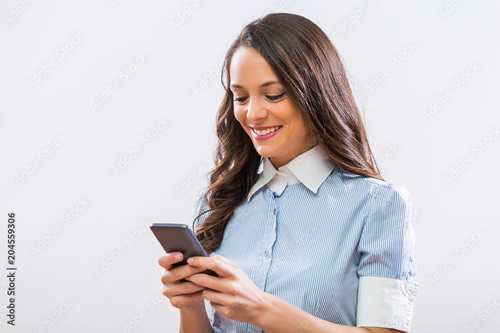 Image of beautiful businesswoman using phone on gray background. Image of beautiful businesswoman using phone on gray background.