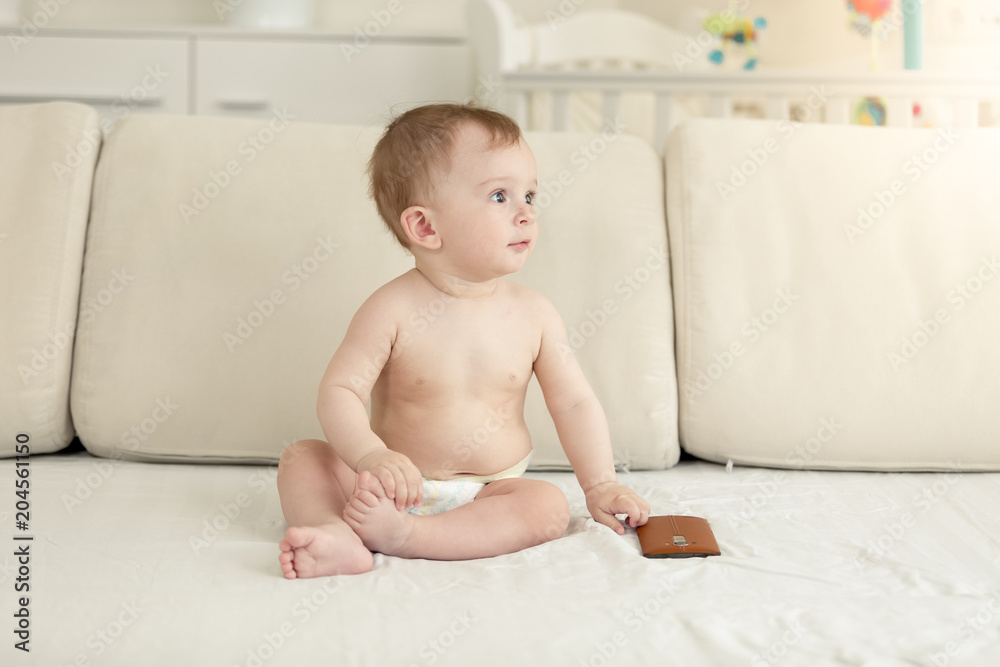 Fototapeta premium Toned photo of cute toddler boy sitting on sofa with smartphone