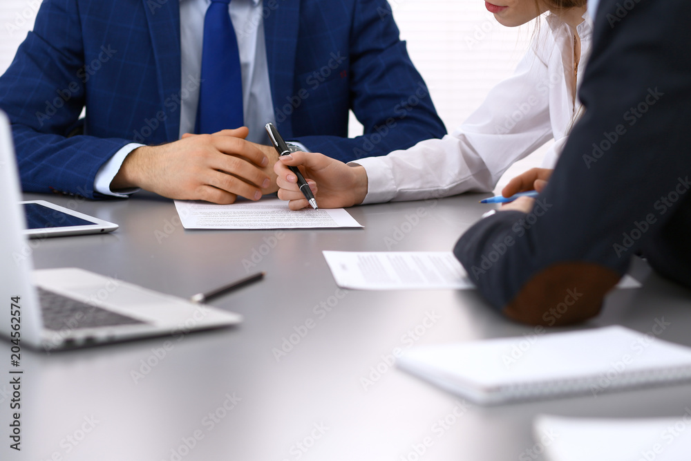 Group of business people and lawyer discussing contract papers sitting at the table, closeup. Businessman is signing document after agreement done Group of business people and lawyer discussing contract papers sitting at the table, closeup. Businessman is signing document after agreement done