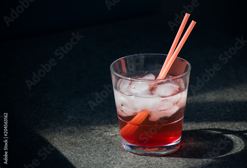 Red Cocktail Lemonade Glass Ice Cubes Straws Isolated Sun Summer Drink Black background Stone