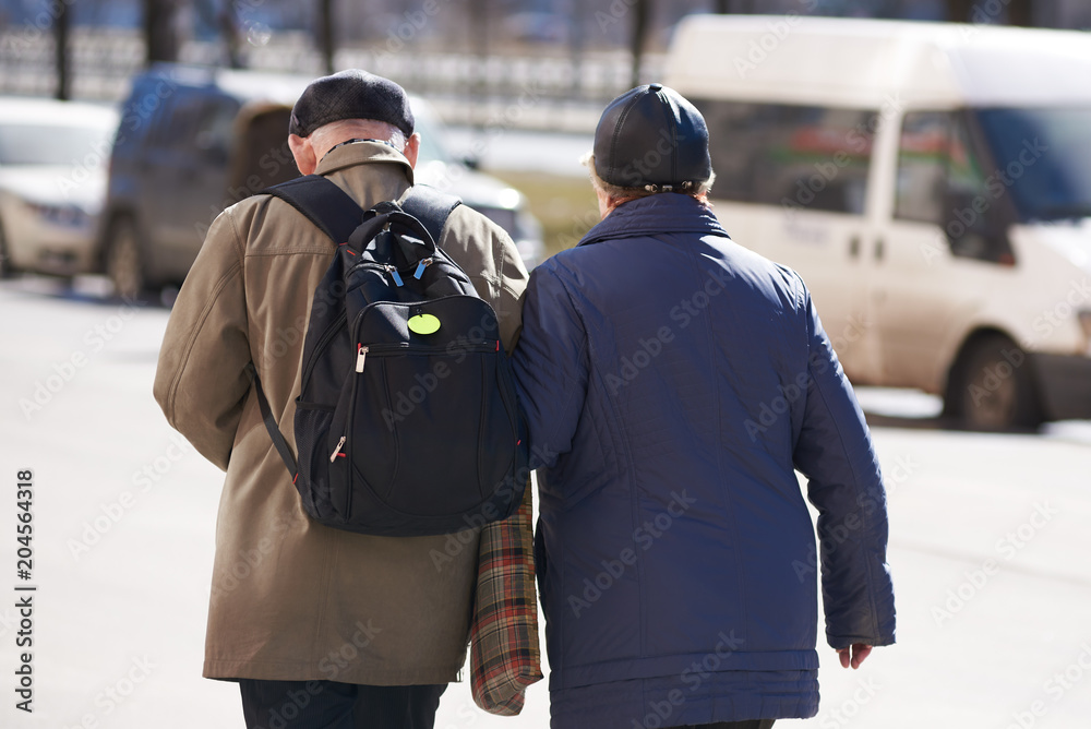 Back view of senior couple taking a walk in a street. She is holding his hand. Back view of senior couple taking a walk in a street. She is holding his hand.