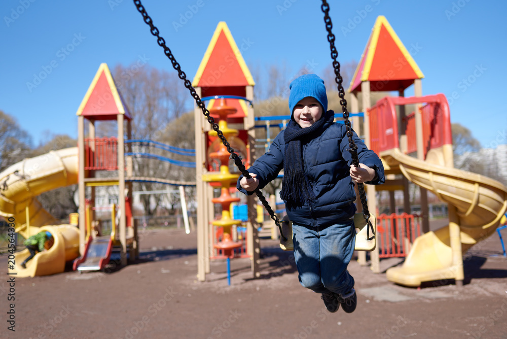 Happy smiling Caucasian boy swinging at a playground. Happy smiling Caucasian boy swinging at a playground.