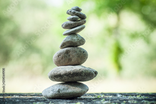 closeup of stones balance on wooden table on green blurred background