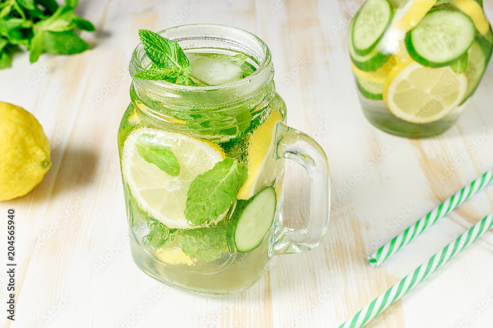 Fototapeta premium Detox water infused with sliced lemon, cucumber and sprigs of mint on wooden background.