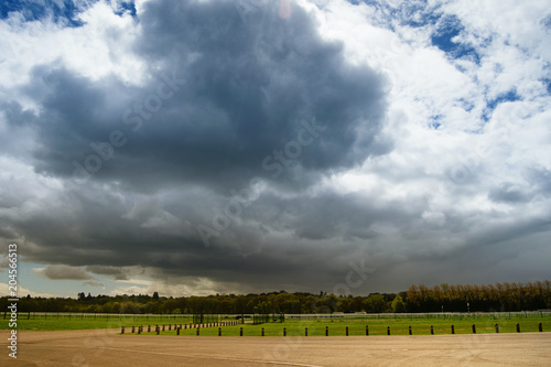 Stadium, field and huge thundery clouds in summer photo