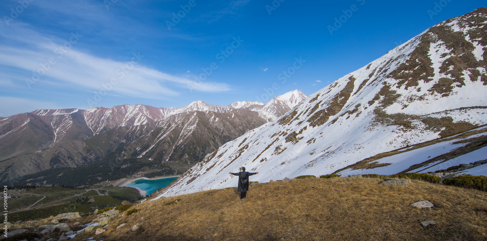 the traveler looks at a mountain lake