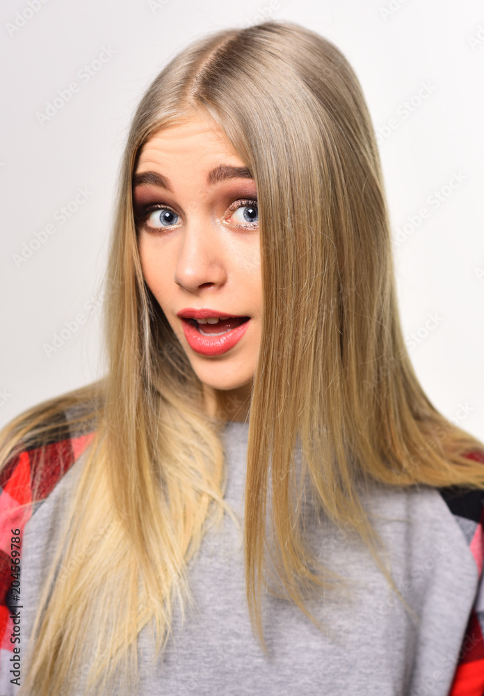 Cheerful young woman with thick eyebrows and long blond shining hair posing in studio isolated on white background Cheerful young woman with thick eyebrows and long blond shining hair posing in studio isolated on white background