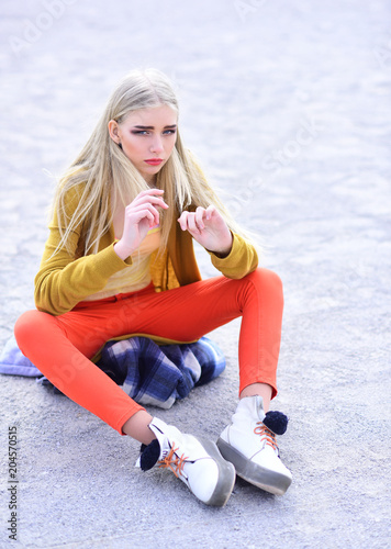 Tableau sur toile Blond model with thick eyebrows and blushed cheeks sitting on sandy road