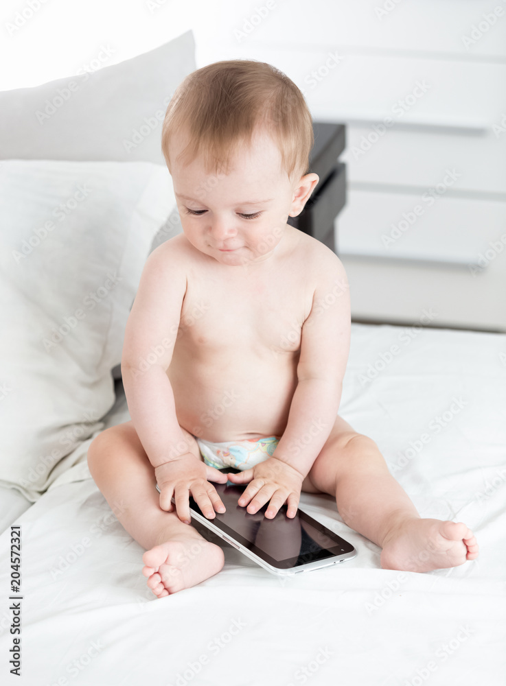 Cute baby boy in diapers on bed with digital tablet computer Cute baby boy in diapers on bed with digital tablet computer