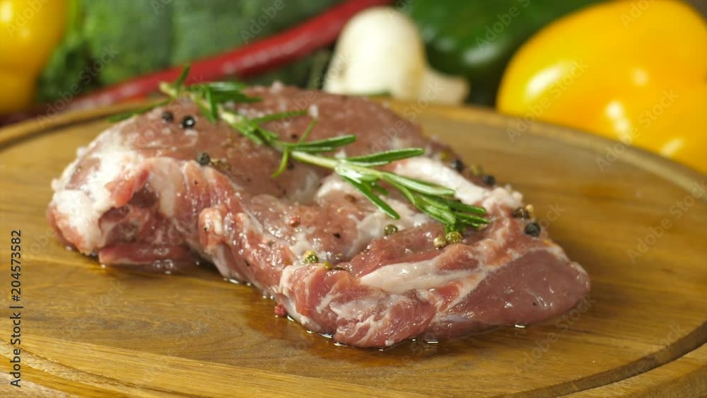 Macro photography of meat marinated with spices lying on a round wooden board, rotation of the board, side view at an angle Macro photography of meat marinated with spices lying on a round wooden board, rotation of the board, side view at an angle