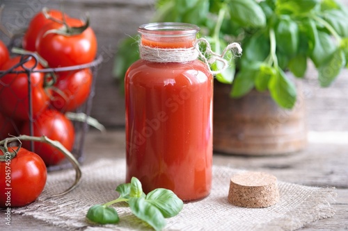 Quadro em tela Tomato juice in glasses and tomato on wooden table on wooden background