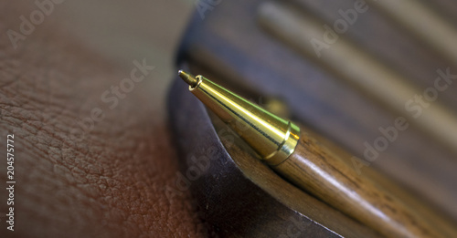 A vintage pen sits on a vintage wooden case that is distressed on a leather topped table 