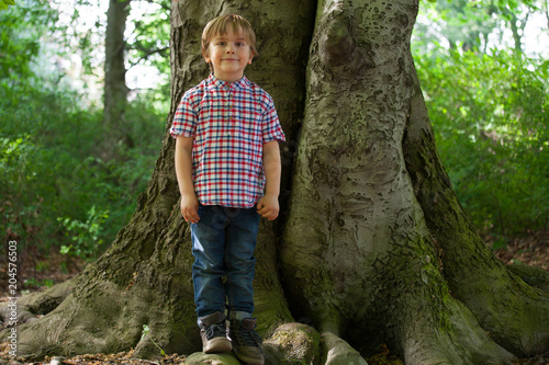 Happy little boy in a forest looking at camera