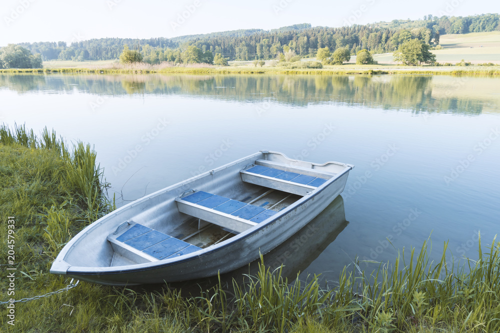 Obraz premium Blaues Holz Boot am Ufer eines Flusses