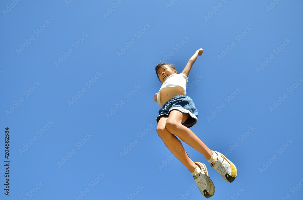 青空でジャンプする女の子