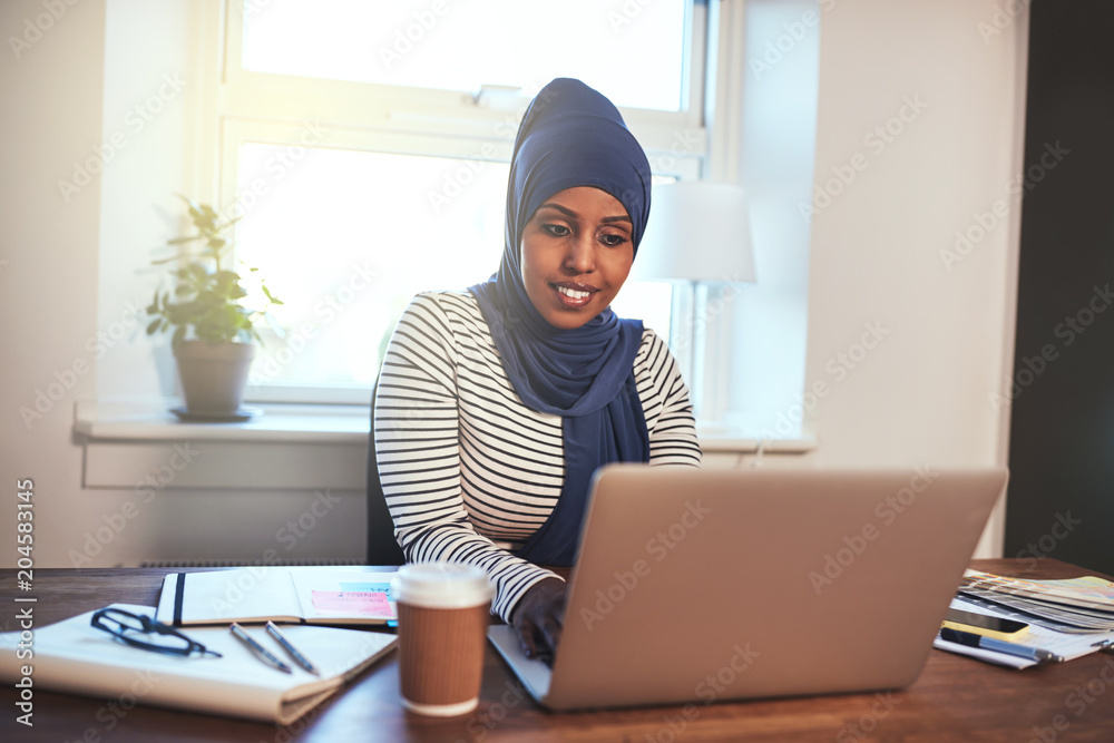 Smiling Arabic female entrepreneur working in her home office Smiling Arabic female entrepreneur working in her home office