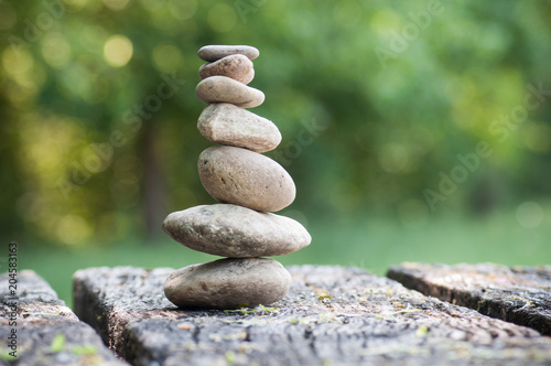 closeup of stones balance on wooden table on green blurred background