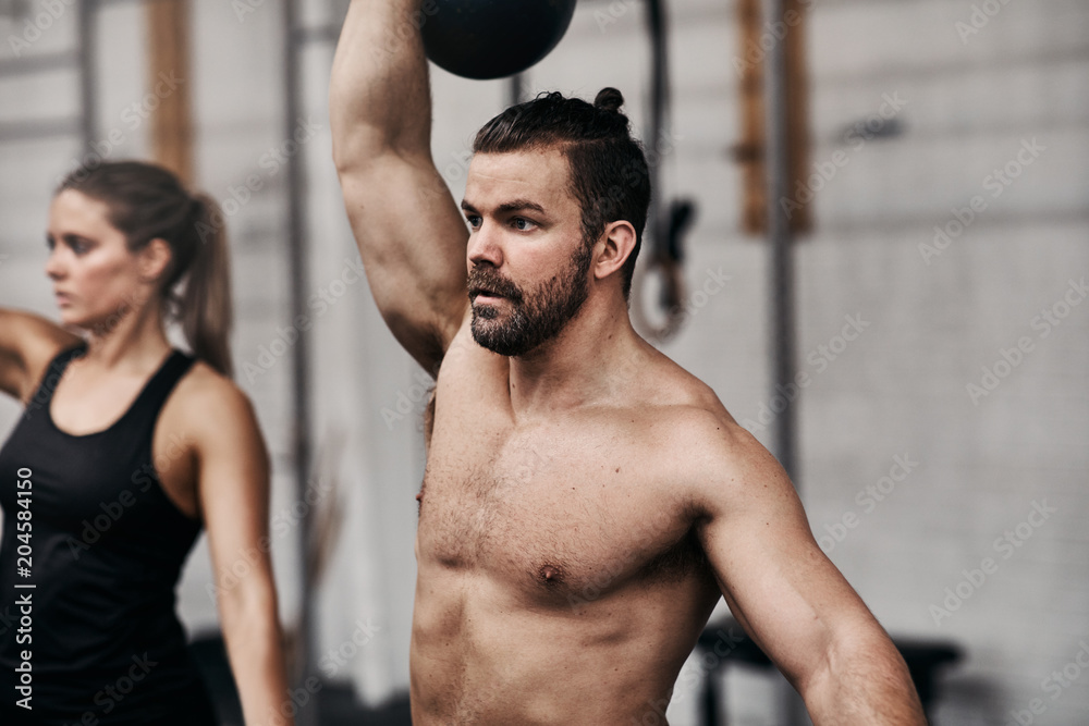 Man lifting a dumbbell over his head at the gym Man lifting a dumbbell over his head at the gym