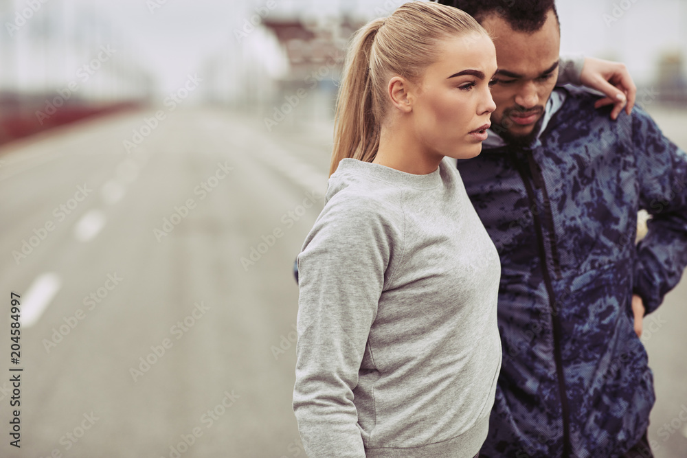 Diverse young couple standing outside together before a run